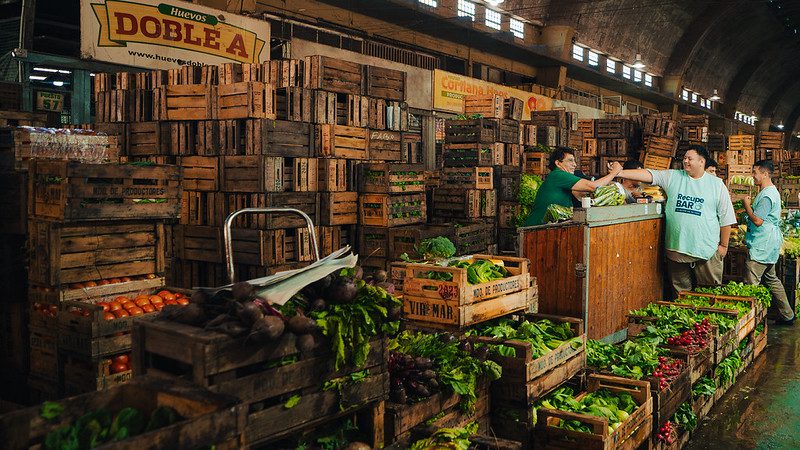 Nico Lopez from Banco de Alimentos Rosario's market recovery program, RecuperBAR, greets a vendor at Mercado de Productores Rosario to begin work.